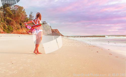 Image of Woman on beach with beach towel flapping behind her