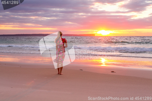 Image of Woman standing on the wet sand of the beach watching sunrise