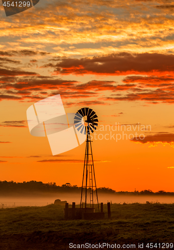 Image of Windmill and misty morning across rural farmland fields