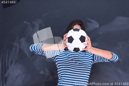 Image of woman holding a soccer ball in front of chalk drawing board