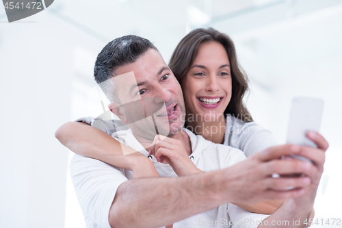 Image of happy couple using mobile phone at home