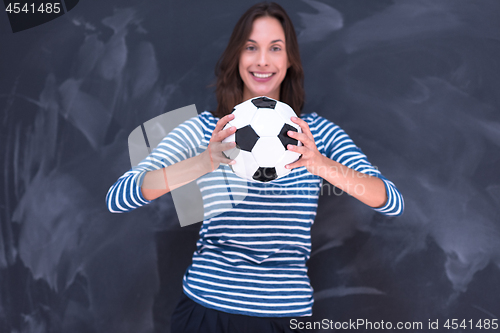 Image of woman holding a soccer ball in front of chalk drawing board