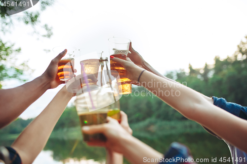 Image of Bottles of beer in people\'s hands on blue sky background