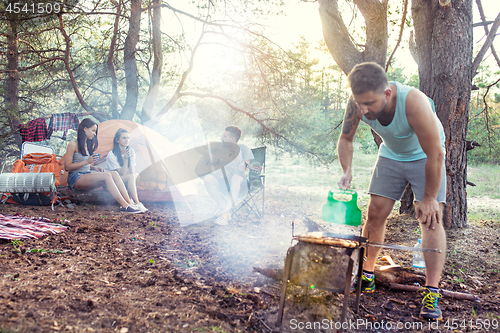 Image of Party, camping of men and women group at forest. They relaxing, singing a song and cooking barbecue