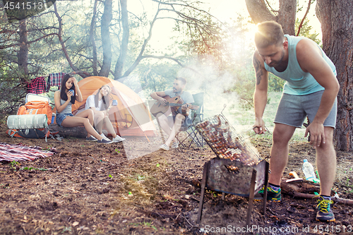 Image of Party, camping of men and women group at forest. They relaxing, singing a song and cooking barbecue