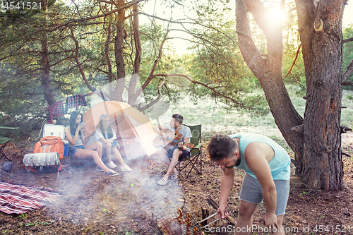 Image of Party, camping of men and women group at forest. They relaxing, singing a song and cooking barbecue