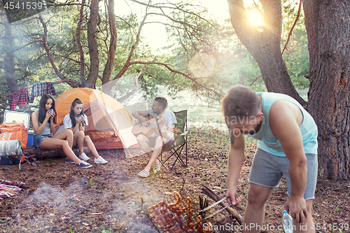 Image of Party, camping of men and women group at forest. They relaxing, singing a song and cooking barbecue