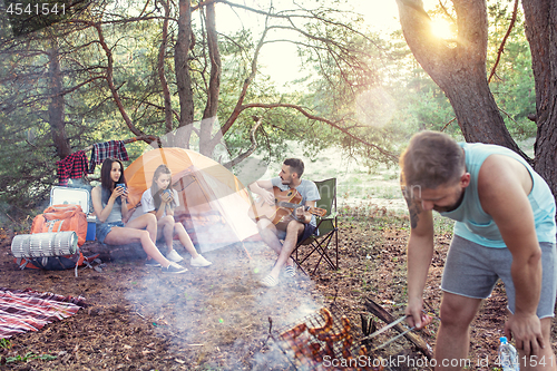 Image of Party, camping of men and women group at forest. They relaxing, singing a song and cooking barbecue