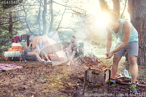 Image of Party, camping of men and women group at forest. They relaxing, singing a song and cooking barbecue