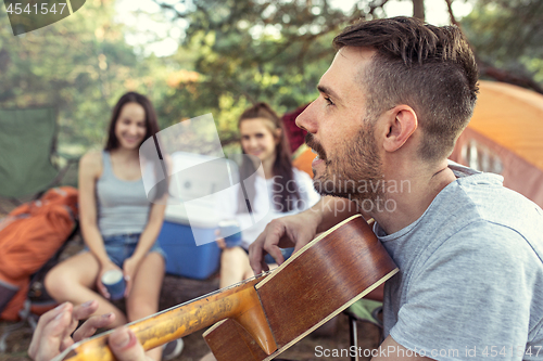 Image of Party, camping of men and women group at forest. They relaxing, singing a song