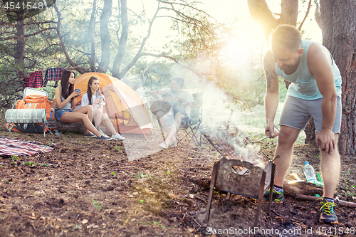 Image of Party, camping of men and women group at forest. They relaxing, singing a song and cooking barbecue