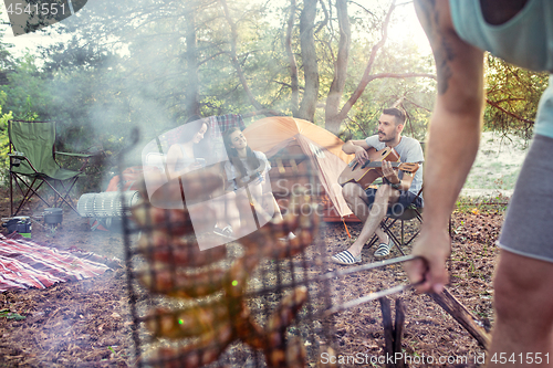 Image of Party, camping of men and women group at forest. They relaxing, singing a song and cooking barbecue