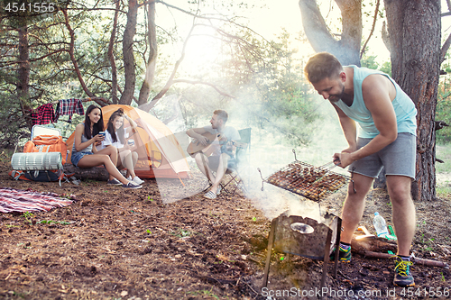 Image of Party, camping of men and women group at forest. They relaxing, singing a song and cooking barbecue