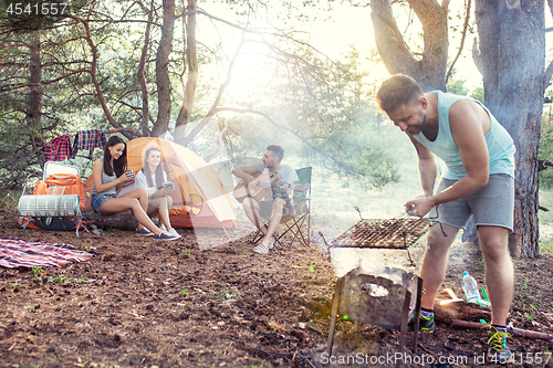 Image of Party, camping of men and women group at forest. They relaxing, singing a song and cooking barbecue