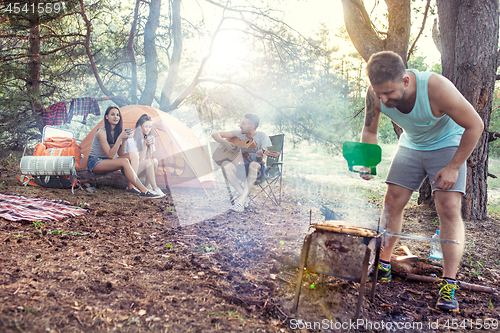 Image of Party, camping of men and women group at forest. They relaxing, singing a song and cooking barbecue