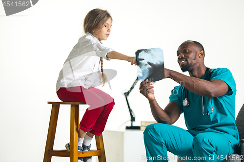 Image of Young african male pediatrician explaining X-ray to child