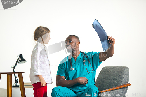 Image of Young african male pediatrician explaining X-ray to child