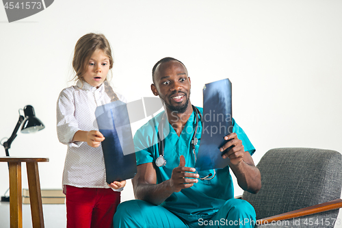 Image of Young african male pediatrician explaining X-ray to child