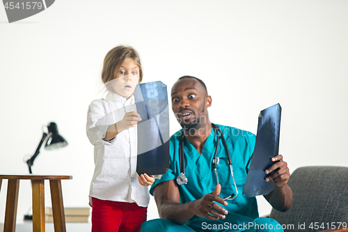 Image of Young african male pediatrician explaining X-ray to child