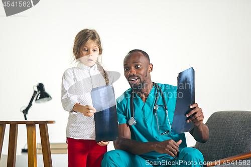 Image of Young african male pediatrician explaining X-ray to child