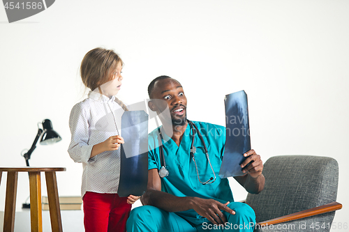 Image of Young african male pediatrician explaining X-ray to child