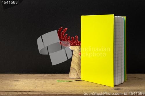 Image of a yellow green note book with hidden reindeer on a wooden table