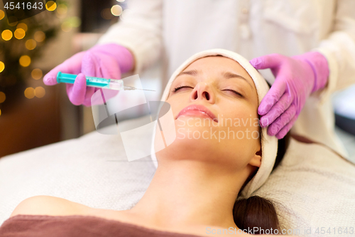 Image of beautician doing beauty injection to woman lips