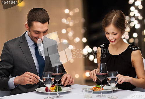 Image of smiling couple eating main course at restaurant