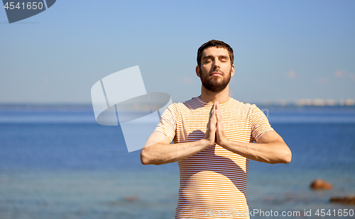 Image of man meditating outdoors over sea