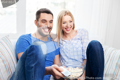 Image of happy couple with popcorn watching tv at home