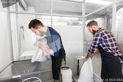 Image of men with malt bags and mill at craft beer brewery