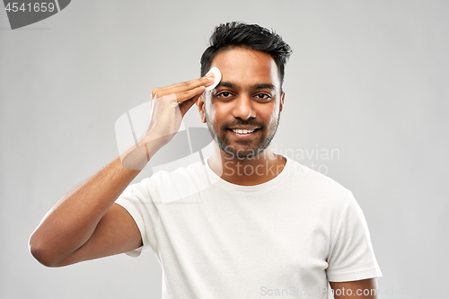 Image of smiling indian man cleaning face with cotton pad