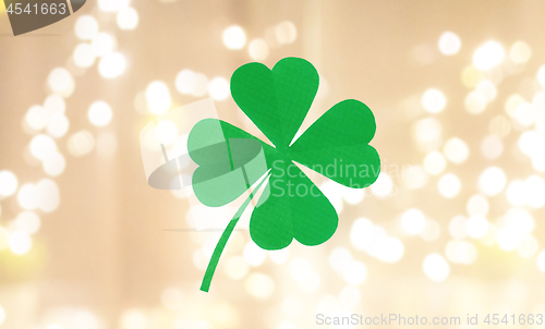 Image of green paper four-leaf clover over festive lights