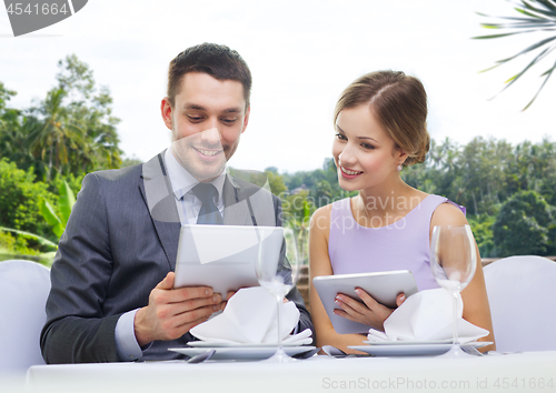 Image of couple with menu on tablet computers at restaurant