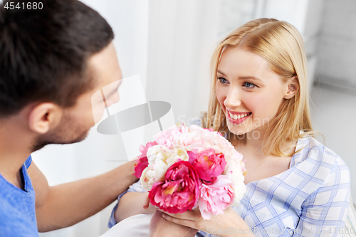 Image of happy couple with flowers at home