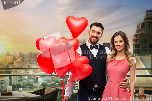 Image of happy couple with red heart shaped balloons