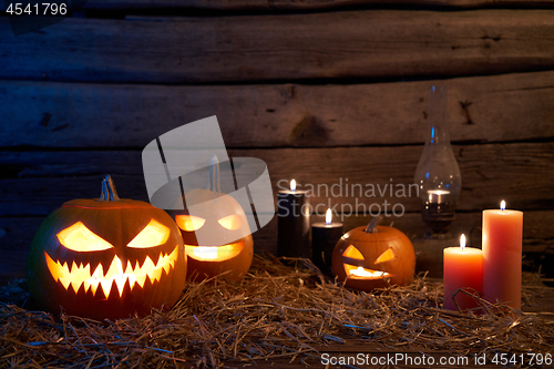 Image of Jack-O-Lantern Halloween pumpkins on rough wooden planks with candles