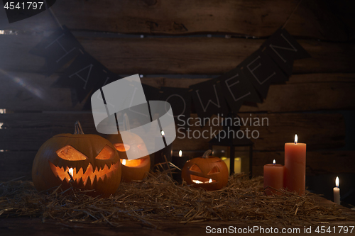 Image of Jack-O-Lantern Halloween pumpkins on rough wooden planks with candles