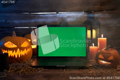 Image of Jack-O-Lantern Halloween pumpkins on rough wooden planks with candles