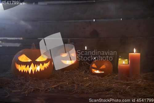 Image of Jack-O-Lantern Halloween pumpkins on rough wooden planks with candles