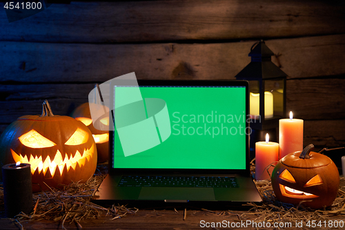 Image of Jack-O-Lantern Halloween pumpkins on rough wooden planks with candles