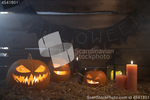 Image of Jack-O-Lantern Halloween pumpkins on rough wooden planks with candles