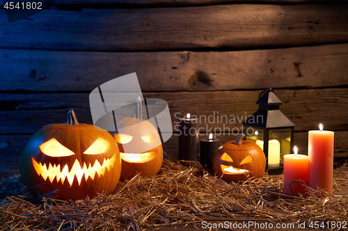 Image of Jack-O-Lantern Halloween pumpkins on rough wooden planks with candles