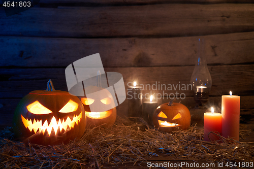 Image of Jack-O-Lantern Halloween pumpkins on rough wooden planks with candles