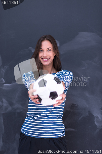 Image of woman holding a soccer ball in front of chalk drawing board