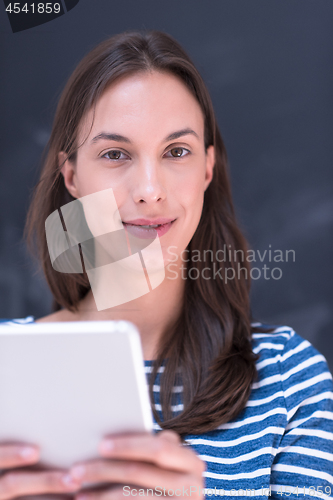 Image of woman using tablet  in front of chalk drawing board