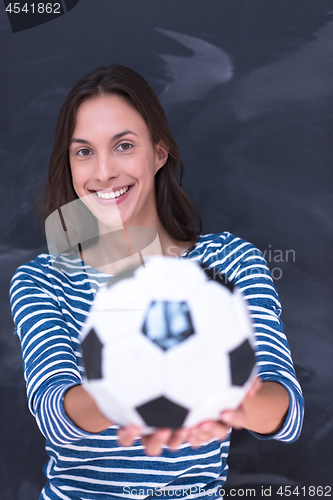 Image of woman holding a soccer ball in front of chalk drawing board