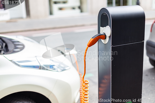 Image of Power supply for electric car charging. Electric car charging station. Close up of the power supply plugged into an electric car being charged.