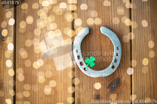 Image of horseshoe with shamrock on wooden background