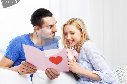 Image of happy couple with greeting card and flowers